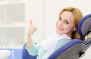 A woman giving a thumb's up in the dental chair
