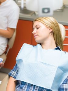 Woman asleep in a dental chair.